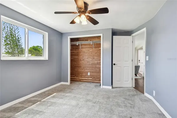 an empty room with windows and fan