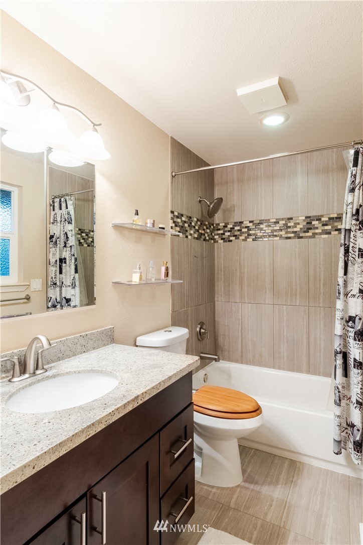 15543 Southeast 169th Street Renton, WA 98058 - Photo 19 of 35 a bathroom with a granite countertop sink toilet a mirror and bathtub