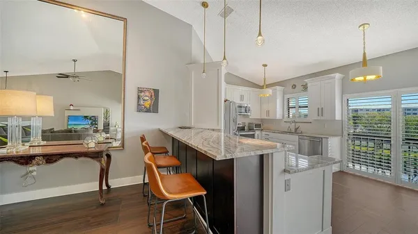 a kitchen with stainless steel appliances kitchen island a table chairs in it and wooden floors