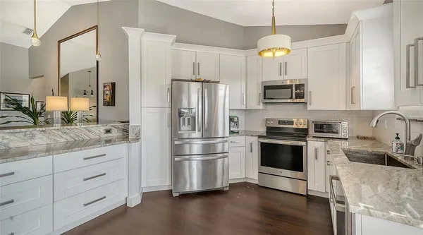 a kitchen with granite countertop a refrigerator stove and sink
