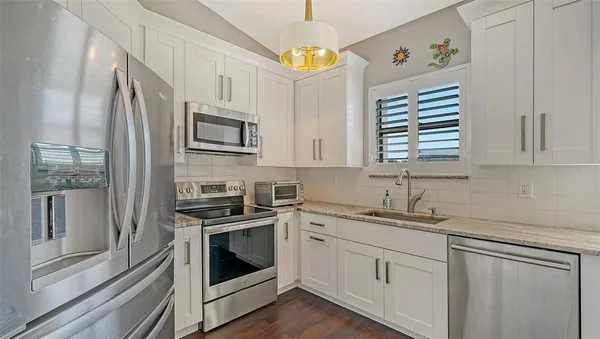 a kitchen with stainless steel appliances granite countertop a sink a stove a microwave and cabinets
