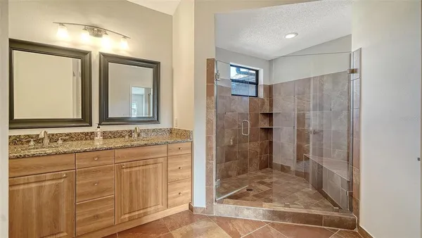 a bathroom with a granite countertop sink a mirror and a shower