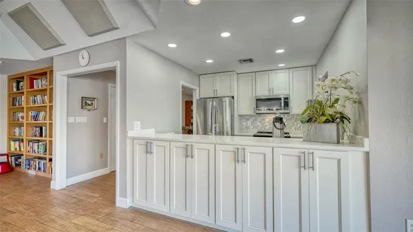 a kitchen with white cabinets and potted plant