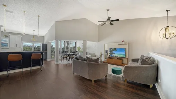 a living room with furniture kitchen view and a wooden floor