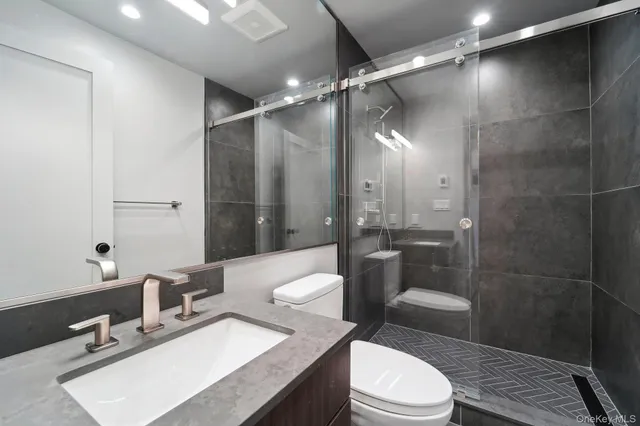 a bathroom with a sink a toilet a mirror and shower
