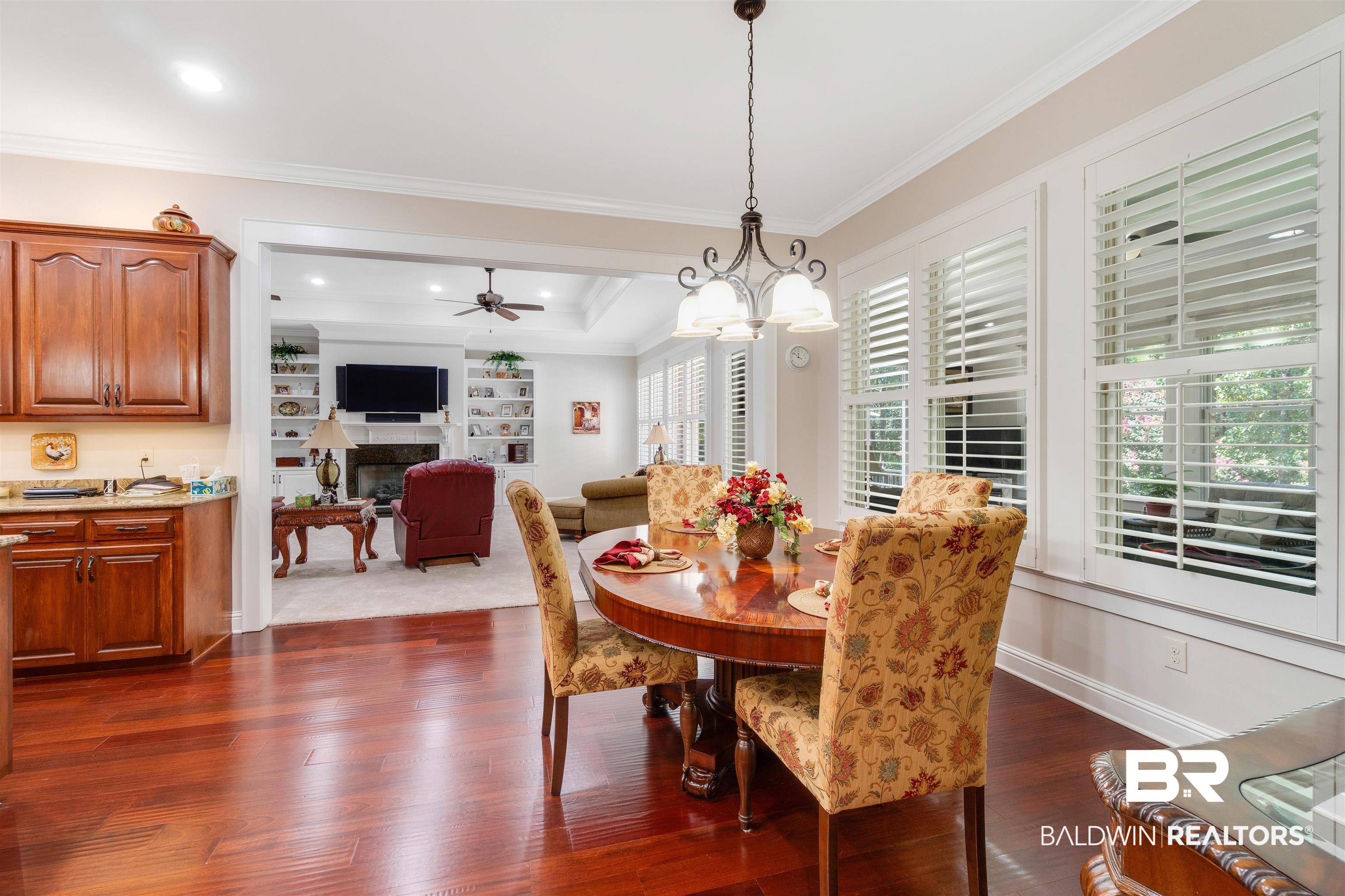 11281 Redfern Road Daphne, AL 36526 - Photo 15 of 80 Dining space with built in features, ceiling fan with notable chandelier, a tray ceiling, dark wood-type flooring, and ornamental molding