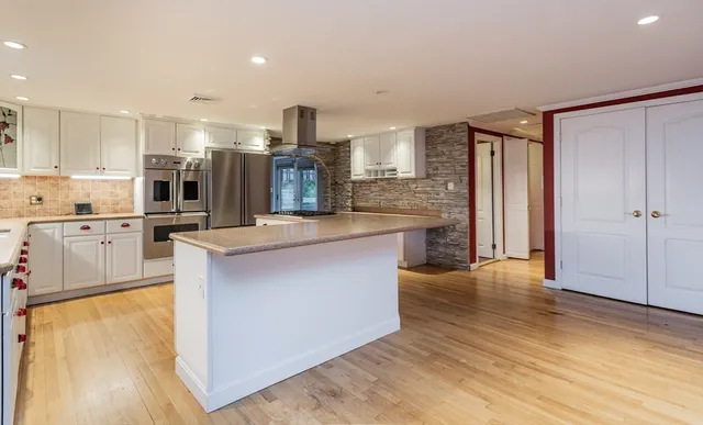 a large kitchen with stainless steel appliances granite countertop a large counter top and a wooden floors
