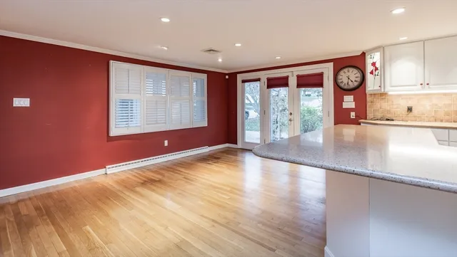 a view of an empty room with window and wooden floor
