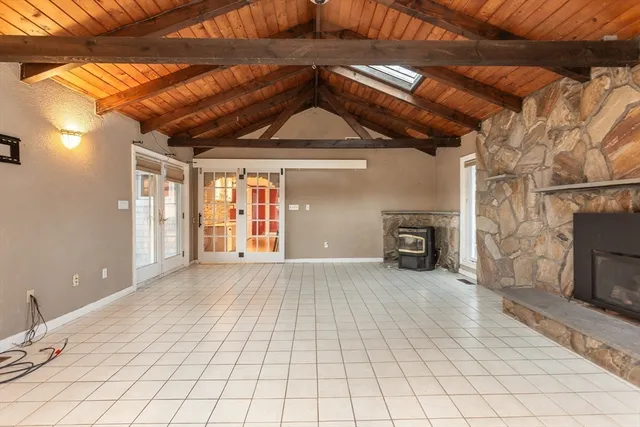 a view of an empty room with wooden floor and a fireplace
