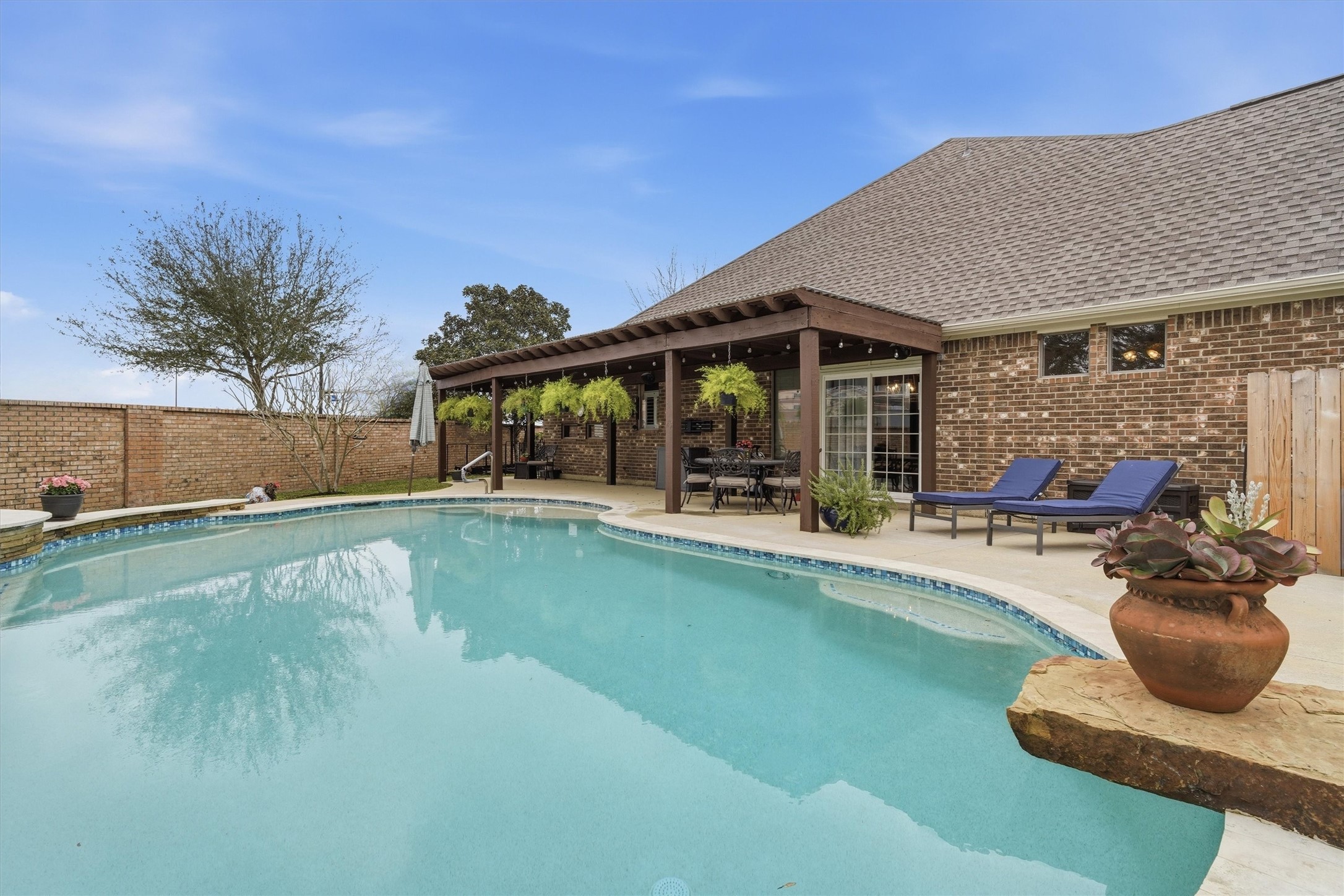 1558 Viejo Road League City, TX 77573 - Photo 2 of 28 Resort-style backyard featuring a sparkling in-ground pool, extended patio, and covered pergola for shaded outdoor living.