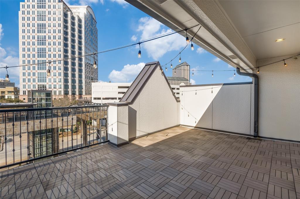 5421 Patterson Street Irving, TX 75039 - Photo 29 of 32 Spacious outdoor terrace with wood-look tile flooring, black metal railings, and string lighting