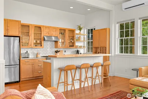 a kitchen with stainless steel appliances granite countertop a stove a refrigerator a kitchen island and chairs in it