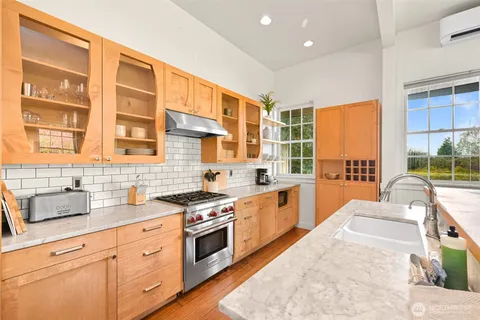 a large kitchen with stainless steel appliances granite countertop a stove a sink and a granite counter tops with wooden floors