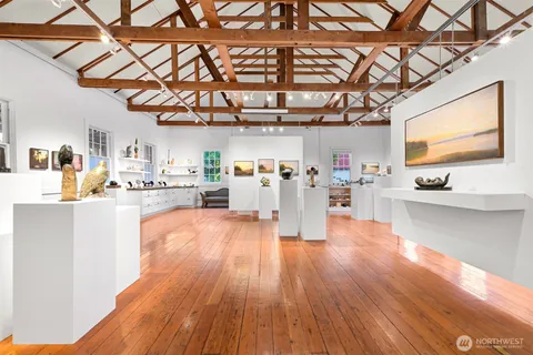 a living room with stainless steel appliances kitchen island granite countertop a table chairs in it and a wooden floor