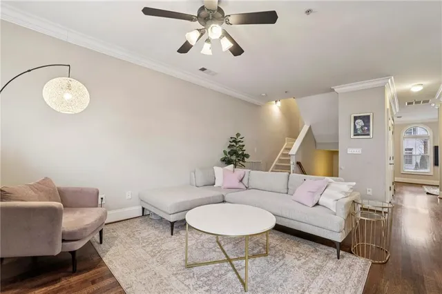 a living room with furniture a chandelier fan and a wooden floor