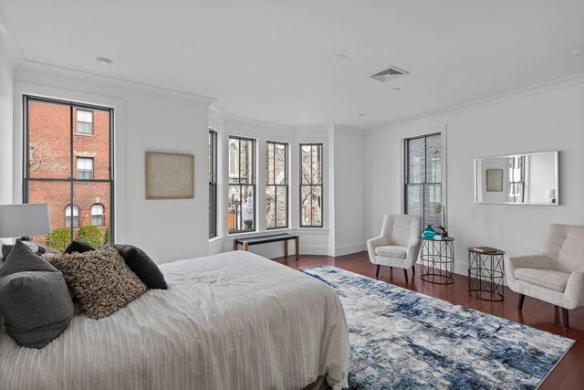 a bedroom with a large bed a rug and windows