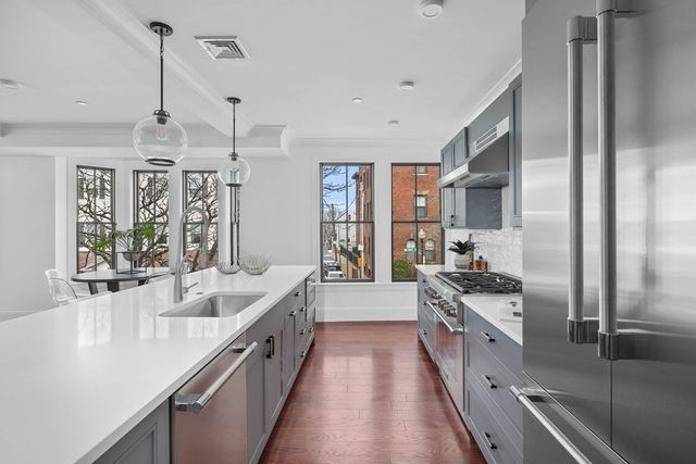 a large kitchen with stainless steel appliances a sink a stove and a wooden floors