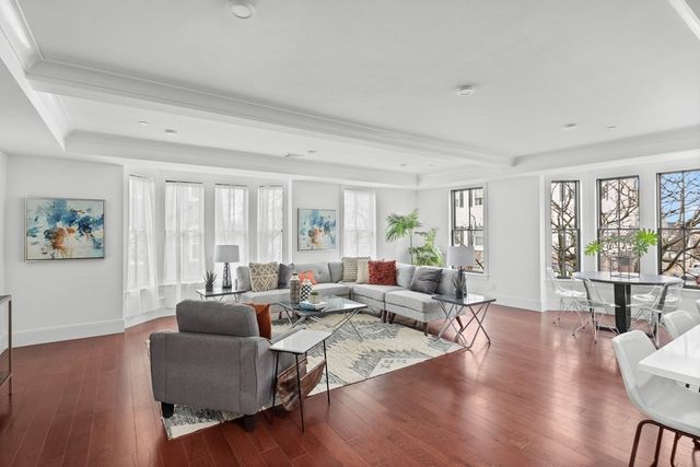 a living room with furniture large window and wooden floor