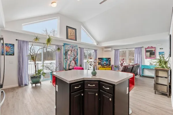 a living room with furniture kitchen view and a wooden floor