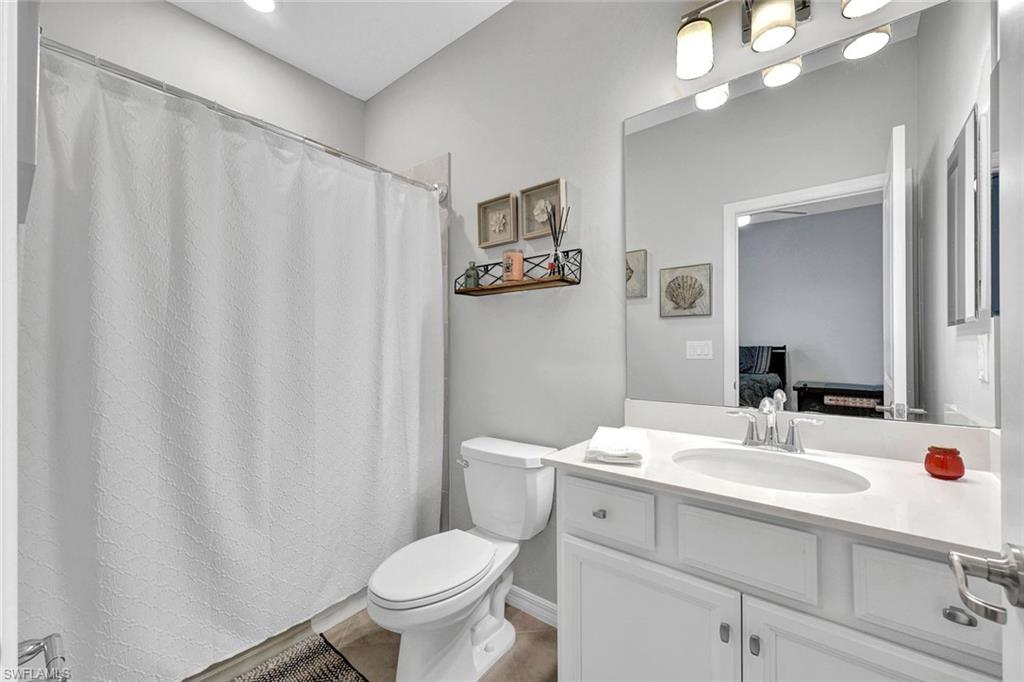 2622 Scarlet Way Naples, FL 34120 - Photo 12 of 24 a bathroom with a sink a toilet a mirror and shower curtain