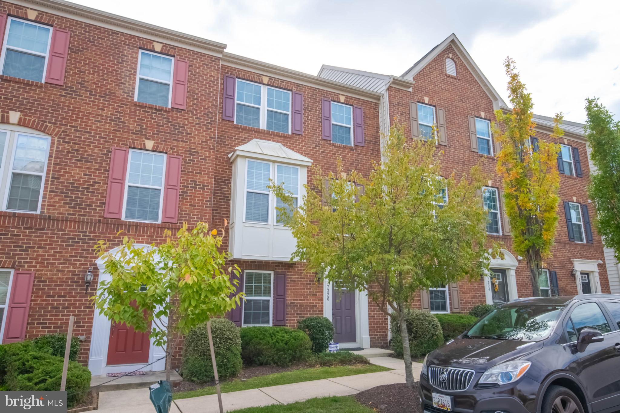 7326 Summit Rock Road Elkridge, MD 21075 - Photo 3 of 40 Charming brick townhomes with vibrant greenery.