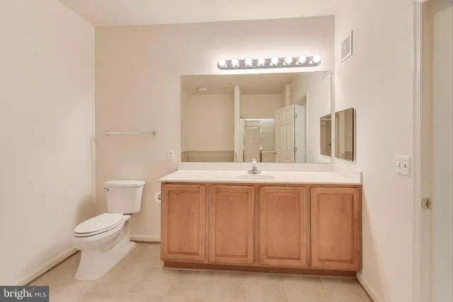 a spacious bathroom with a double vanity sink a toilet and a mirror