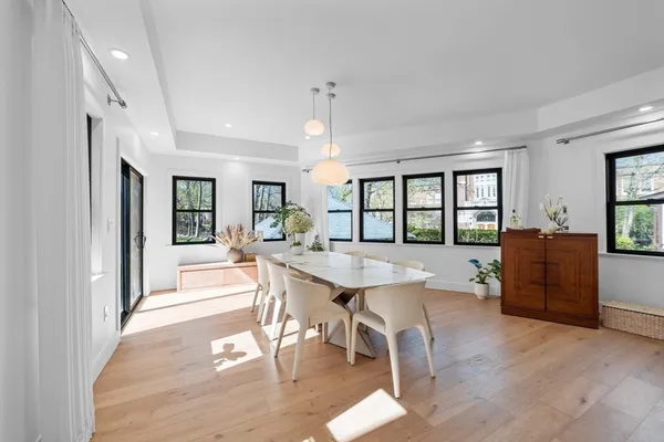 a dining hall with stainless steel appliances kitchen island granite countertop a refrigerator a stove a dining table and chairs with wooden floor