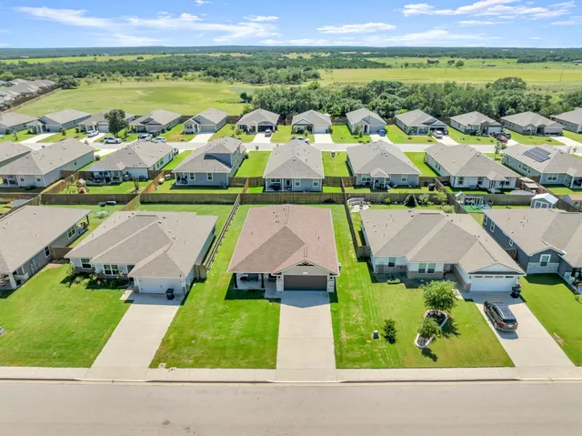 an aerial view of residential houses with outdoor space and parking