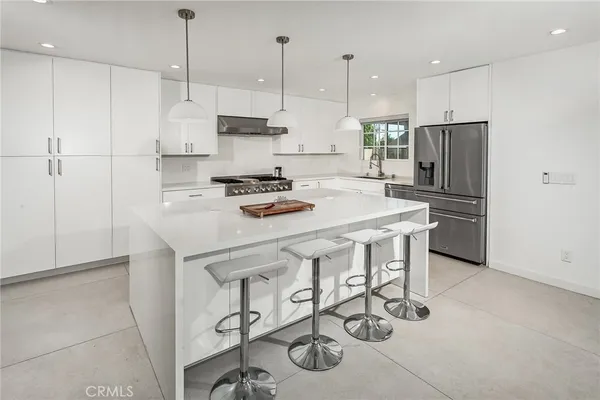 a kitchen with stainless steel appliances granite countertop a sink a stove a refrigerator and white cabinets with wooden floor
