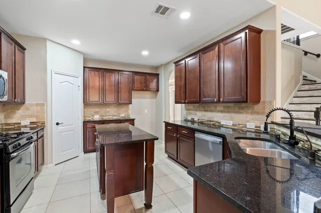 a kitchen with stainless steel appliances granite countertop a sink a stove and a microwave