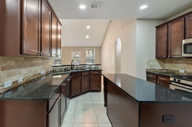a kitchen with stainless steel appliances granite countertop a stove microwave and sink