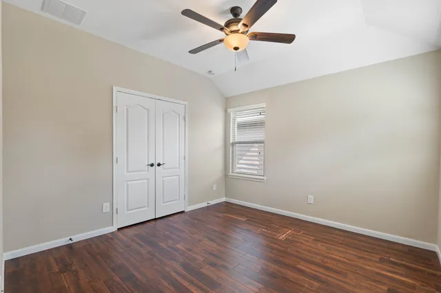 a view of an empty room with window and a chandelier fan