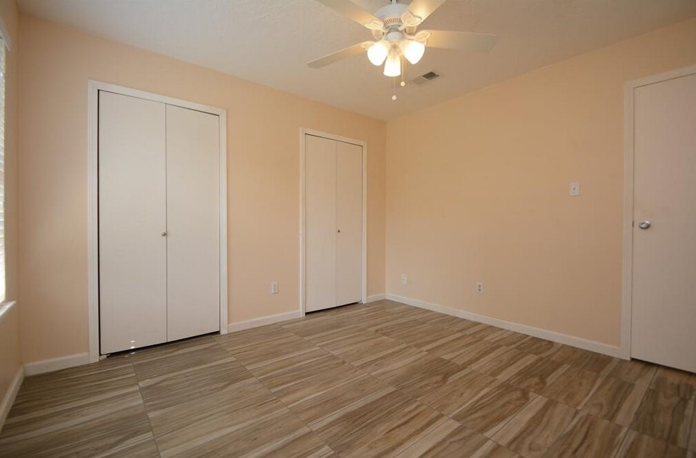 15 South Tallowberry Drive Spring, TX 77381 - Photo 15 of 26 Room with light beige walls, wood-look tile flooring, two closets, a ceiling fan with light, and a window for natural light.