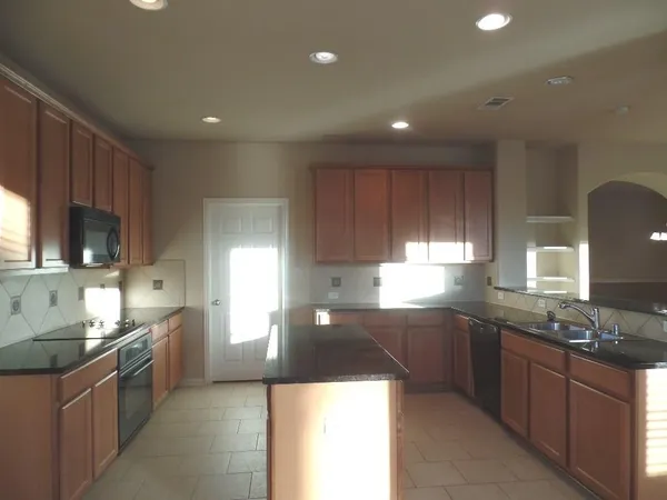 a large kitchen with stainless steel appliances granite countertop a sink a stove a refrigerator and a microwave