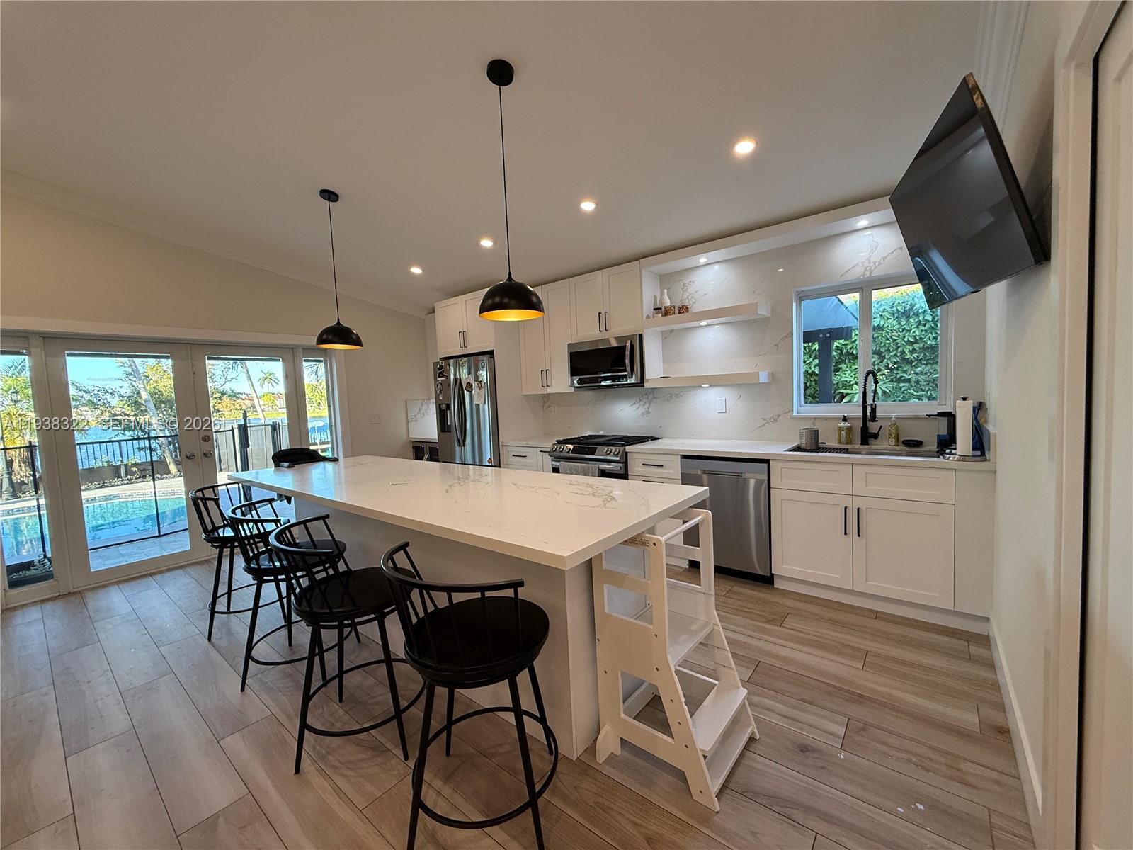 8335 Northwest 197th Terrace Hialeah, FL 33015 - Photo 11 of 51 a kitchen with stainless steel appliances kitchen island granite countertop a table chairs and a wooden floor