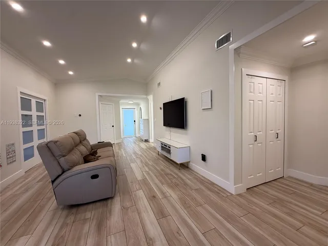 a living room with couches and kitchen view with wooden floor