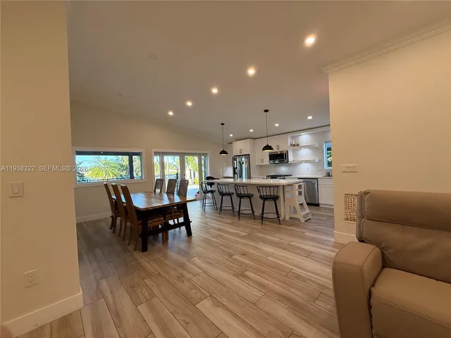 a kitchen with stainless steel appliances a dining table chairs microwave and refrigerator