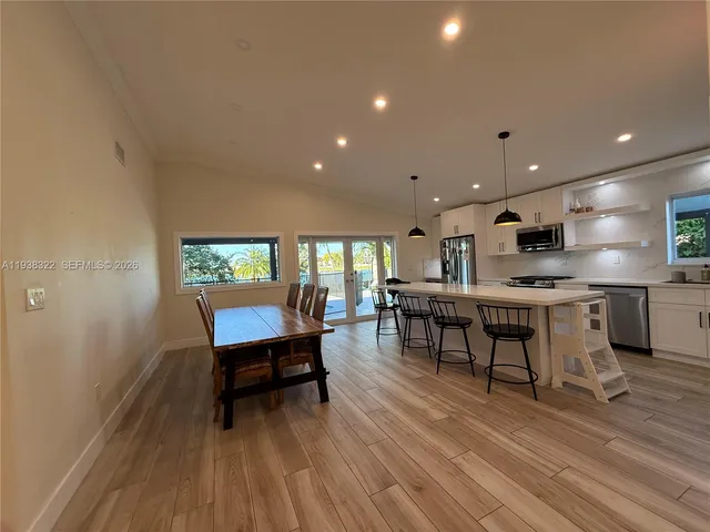 a kitchen with stainless steel appliances kitchen island granite countertop a table chairs and a wooden floor