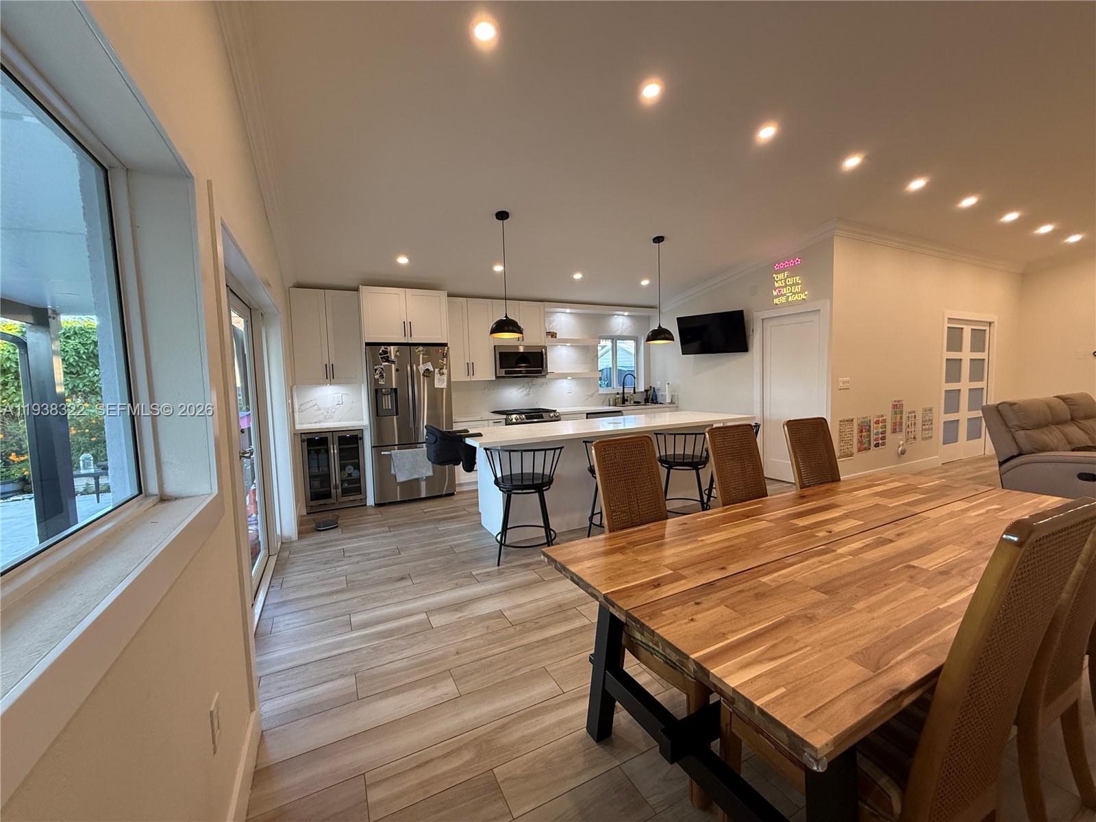 8335 Northwest 197th Terrace Hialeah, FL 33015 - Photo 7 of 51 a large kitchen with kitchen island a stove a sink a refrigerator and a dining table with wooden floor