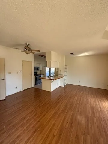 a view of kitchen and empty room with wooden floor
