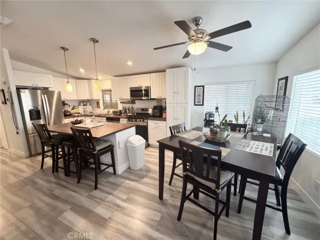 a dining room with stainless steel appliances kitchen island granite countertop a dining table chairs and a oven