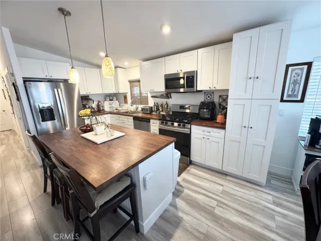 a kitchen with stainless steel appliances granite countertop a stove a refrigerator a kitchen island a sink dishwasher and white cabinets with wooden floor