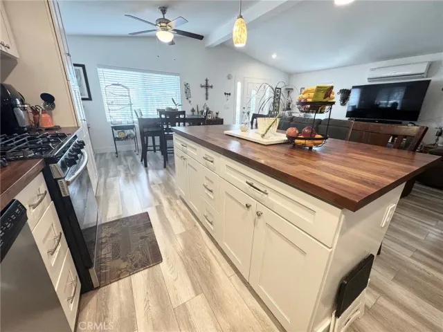 a kitchen with kitchen island granite countertop a stove a sink a oven and a dining table with wooden floor