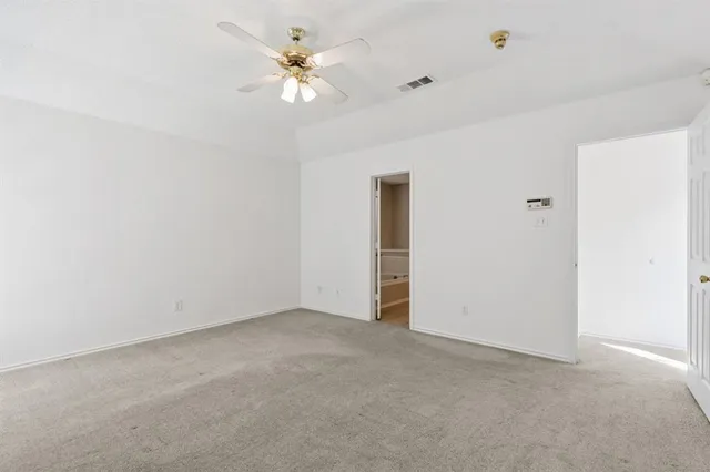 an empty room with a chandelier fan and windows