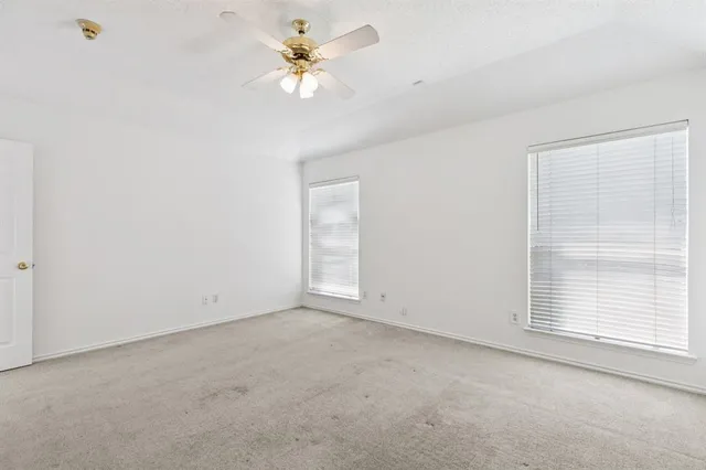 an empty room with a ceiling fan and a window