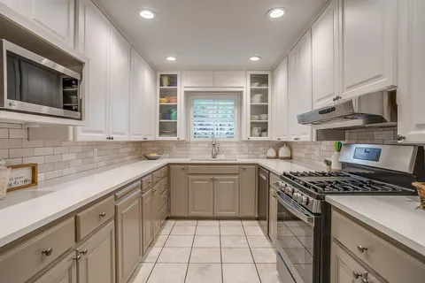 a kitchen with stainless steel appliances granite countertop a sink a stove a microwave and cabinets