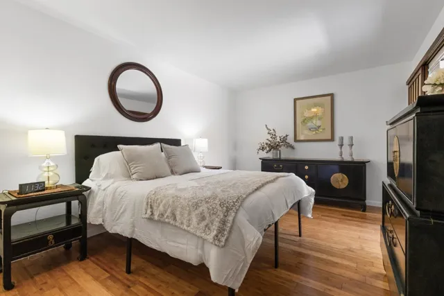 a bedroom with a bed a mirror on dresser and a window