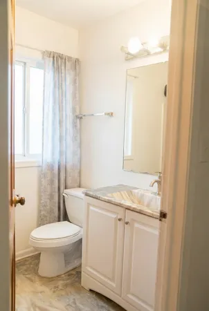 a bathroom with a granite countertop toilet a sink and a shower