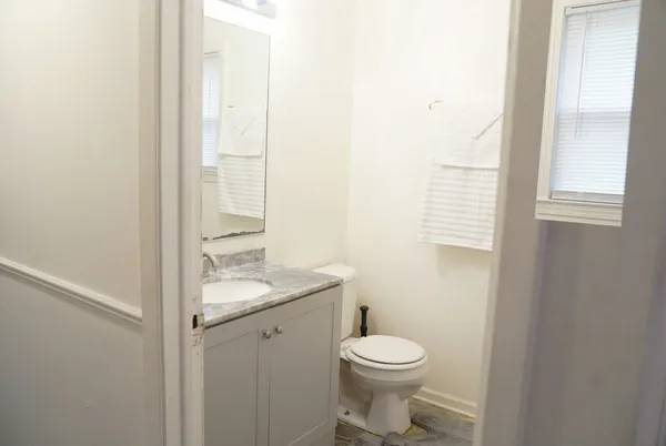 a bathroom with a granite countertop toilet a sink and a window