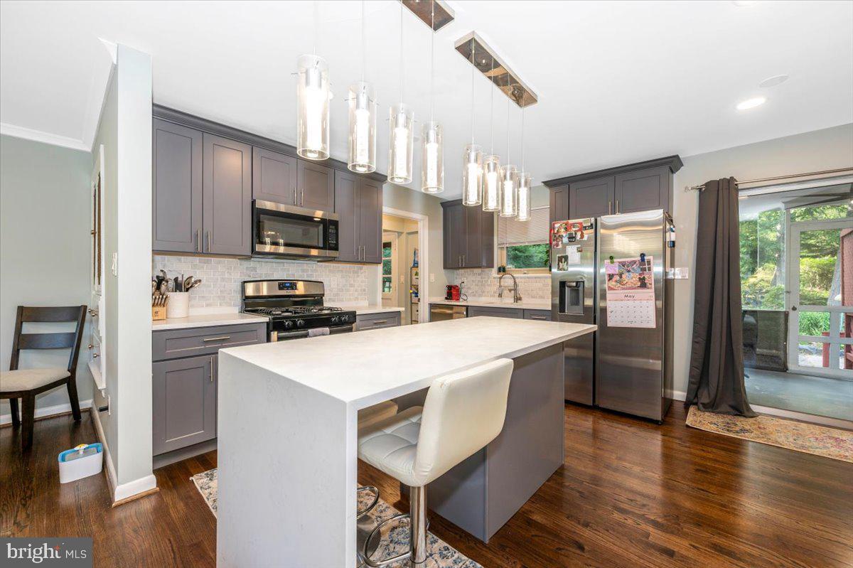 2208 Muskogee Street Adelphi, MD 20783 - Photo 20 of 71 a kitchen with stainless steel appliances a microwave a stove a sink dishwasher a refrigerator white cabinets and wooden floor next to a window
